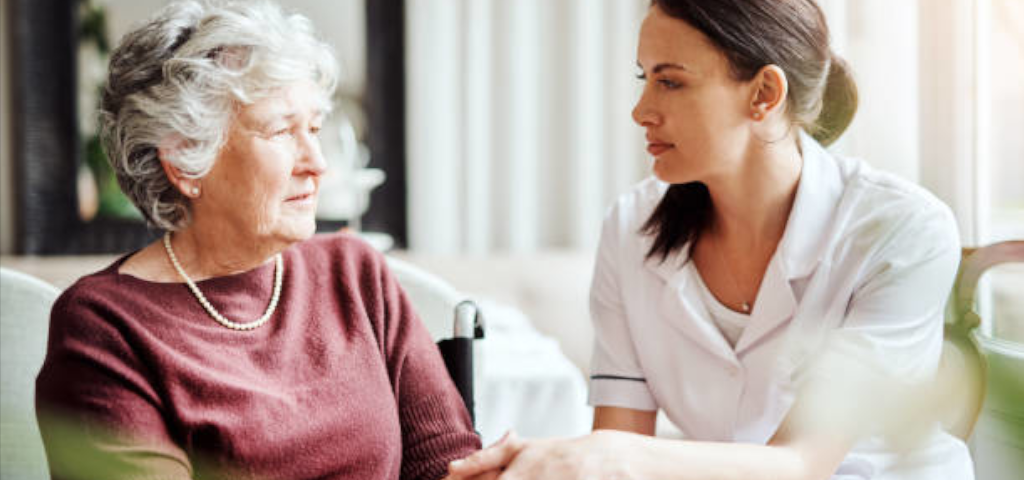 A young nurse holds hands with an elderly woman.