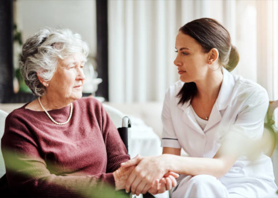 A young nurse holds hands with an elderly woman.