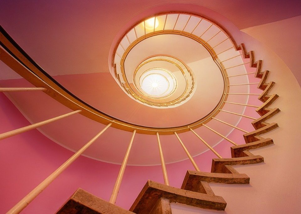 Stairs spiraling up through a pink morning glow toward the light at the top.