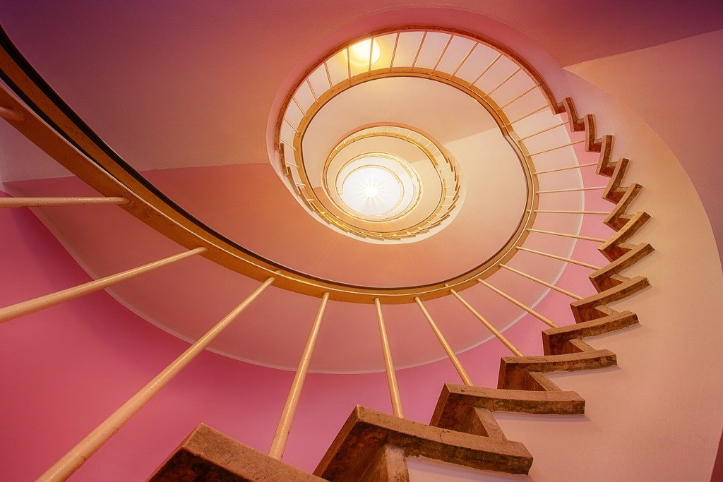 Stairs spiraling up through a pink morning glow toward the light at the top.