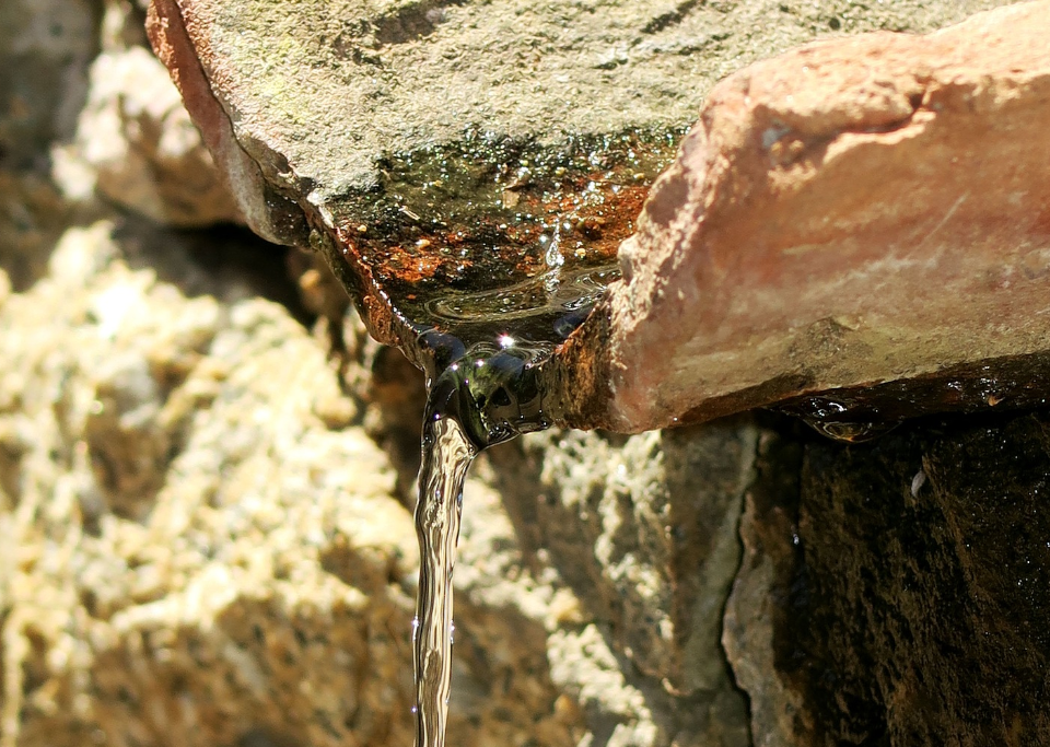 Dry rocks with a small, thin ribbon of water running off the edge.