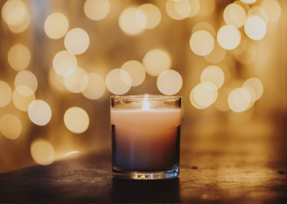 A little candle in the foreground, a net of light blurred in the background.