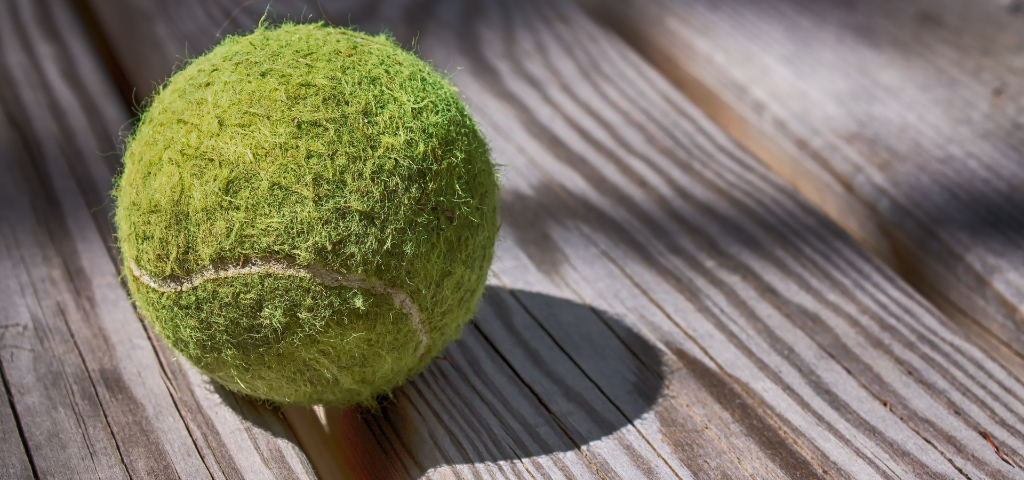 Forgotten tennis ball sitting on a wood deck