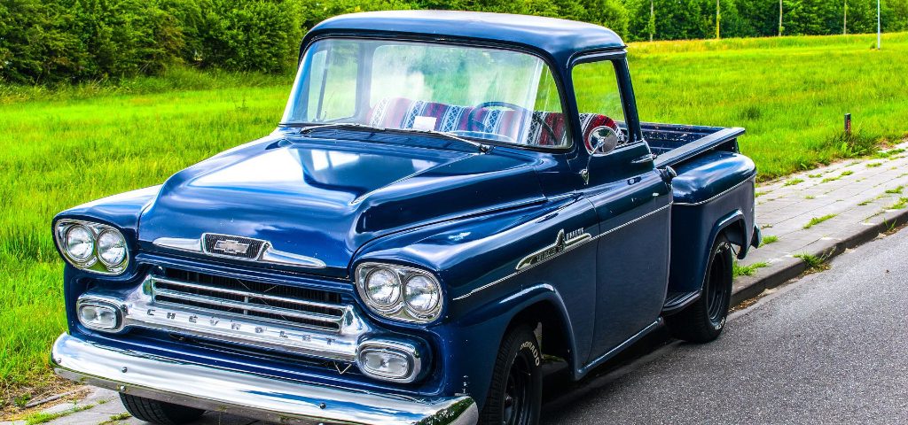 Decorative, old pick up truck parked up on a curb.