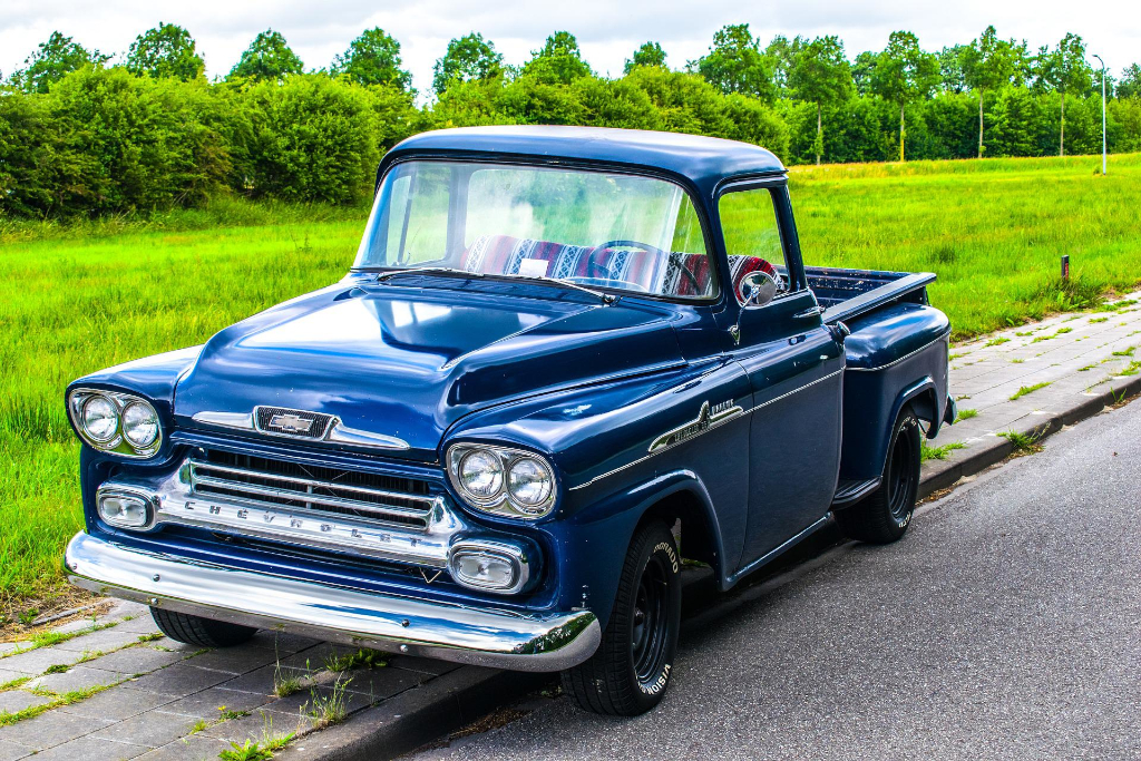 Decorative, old pick up truck parked up on a curb.